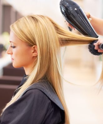 Young woman having her hair blow-dried while at the hair salon